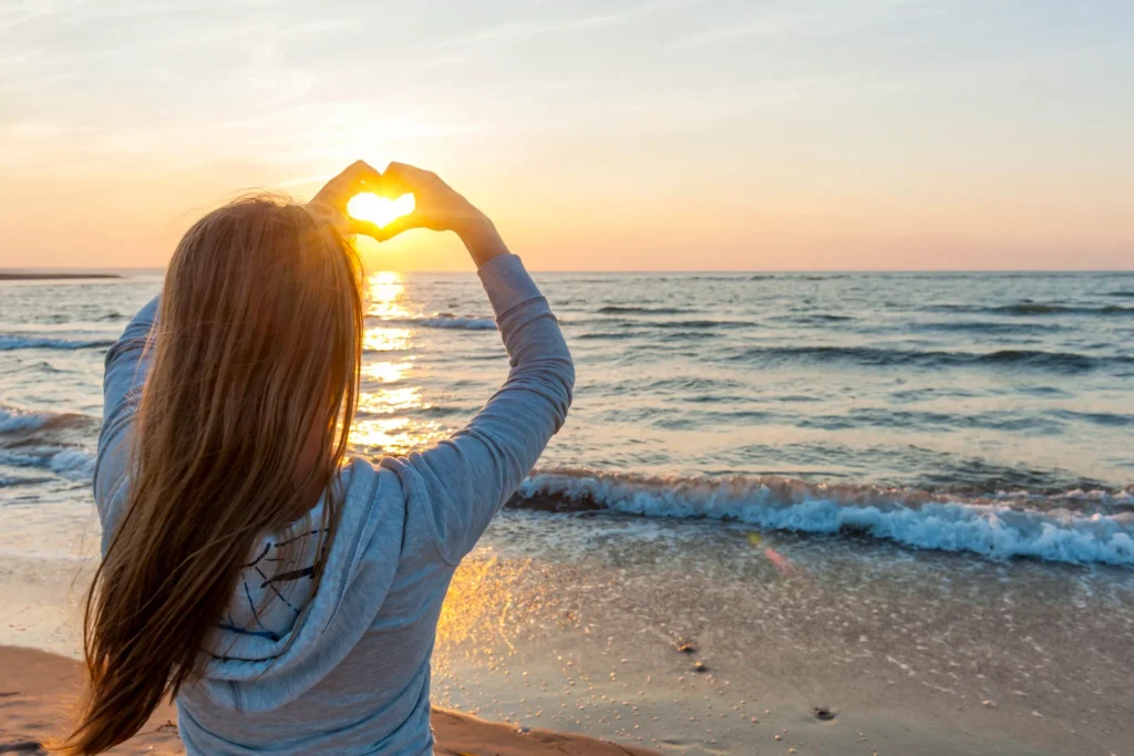 bounce back from failure, woman facing sun neae sea